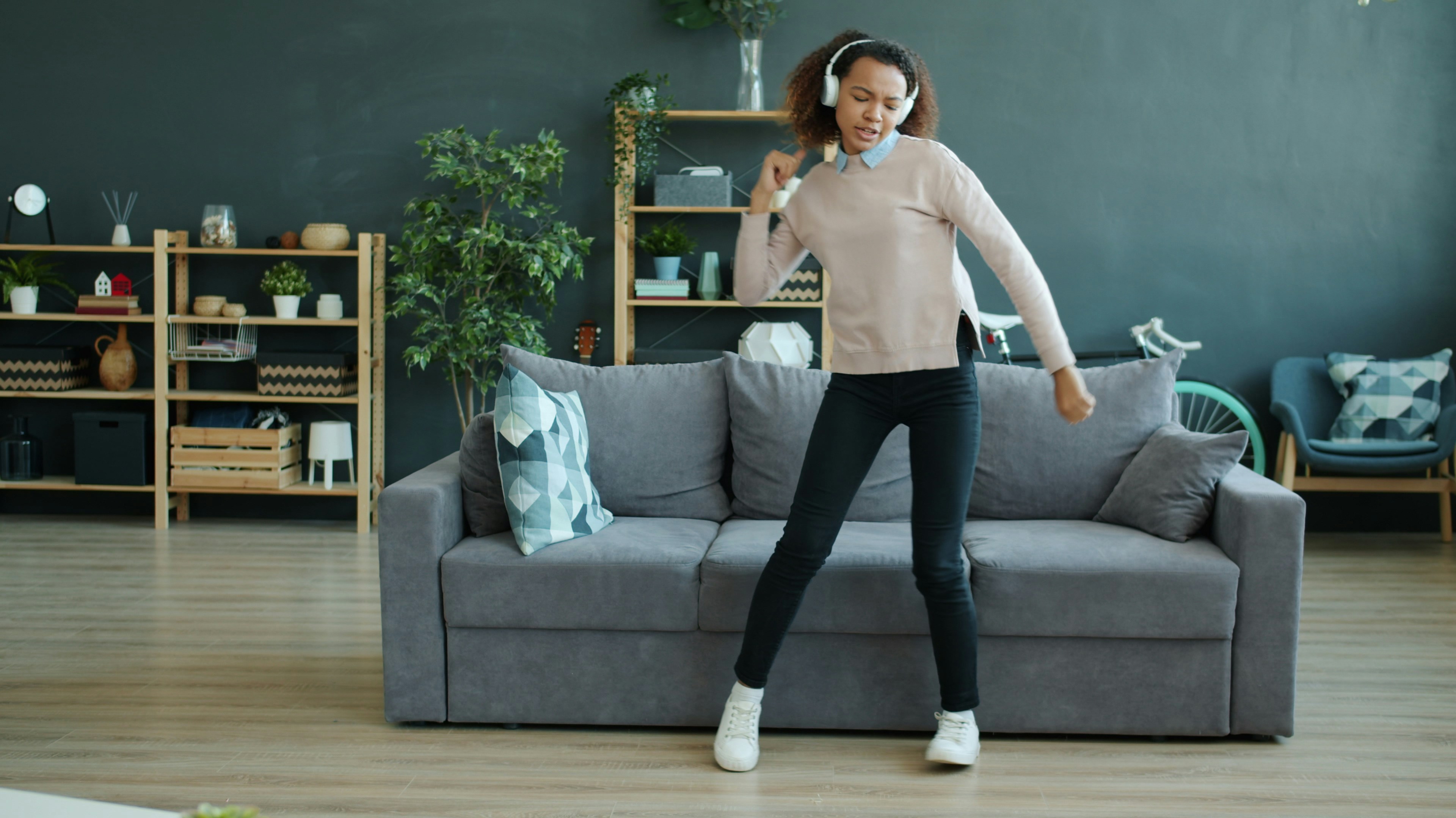 Wanita muda menari sambil mendengarkan musik
