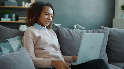 Young woman smiling while using a laptop on the couch