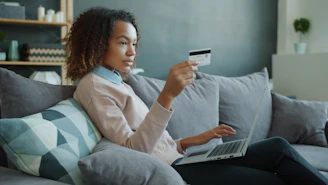 Mujer latina joven gestionando sus finanzas con laptop y tarjeta, organizando su dinero y ahorros