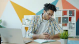 Man working at a desk with laptop and notebook.