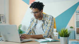 Man with dreadlocks working on a laptop in an office