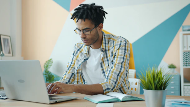 Man with dreadlocks working on a laptop in an office