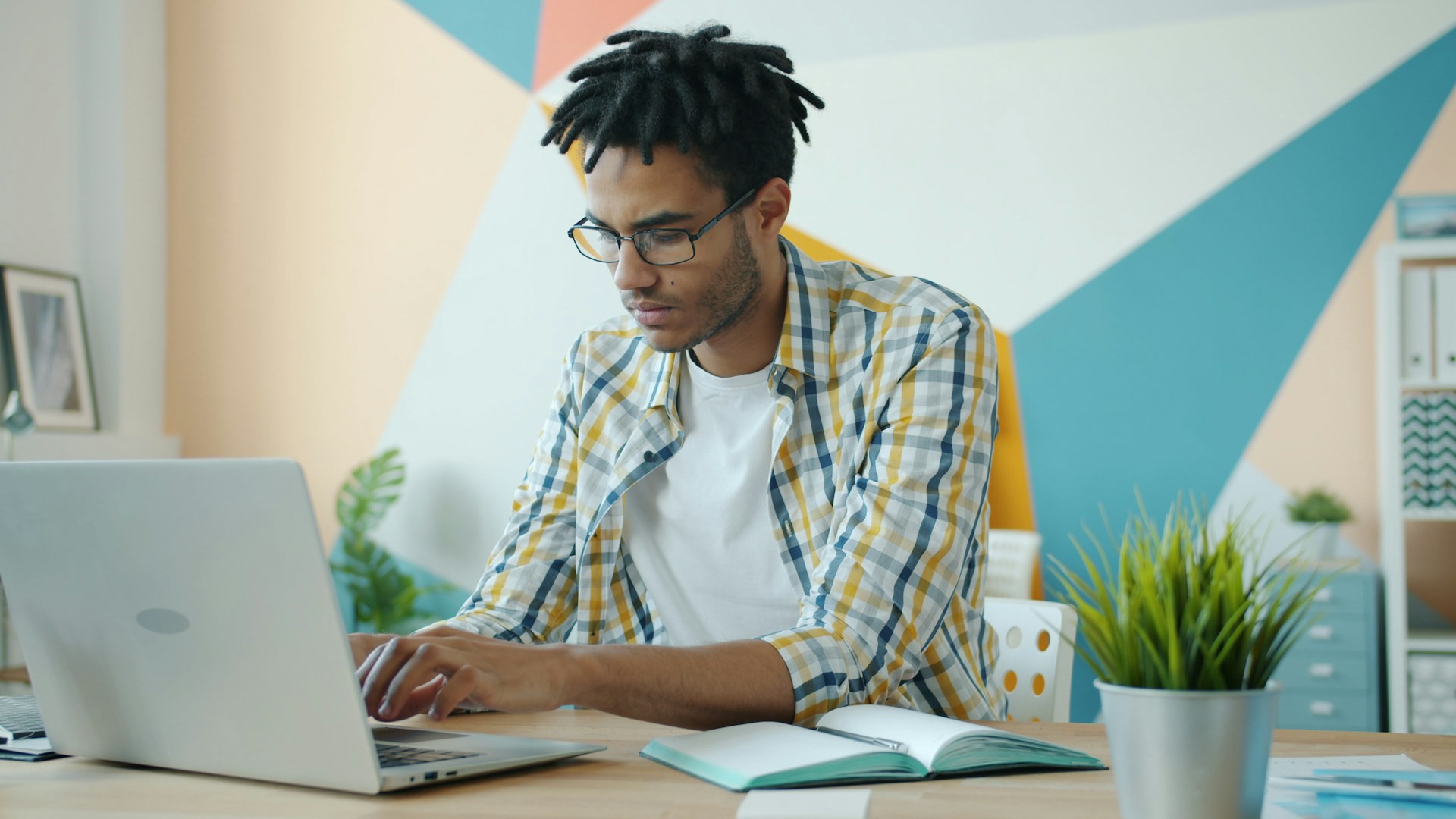 Man with dreadlocks working on a laptop in an office