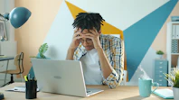Man holding head in frustration at desk with laptop.