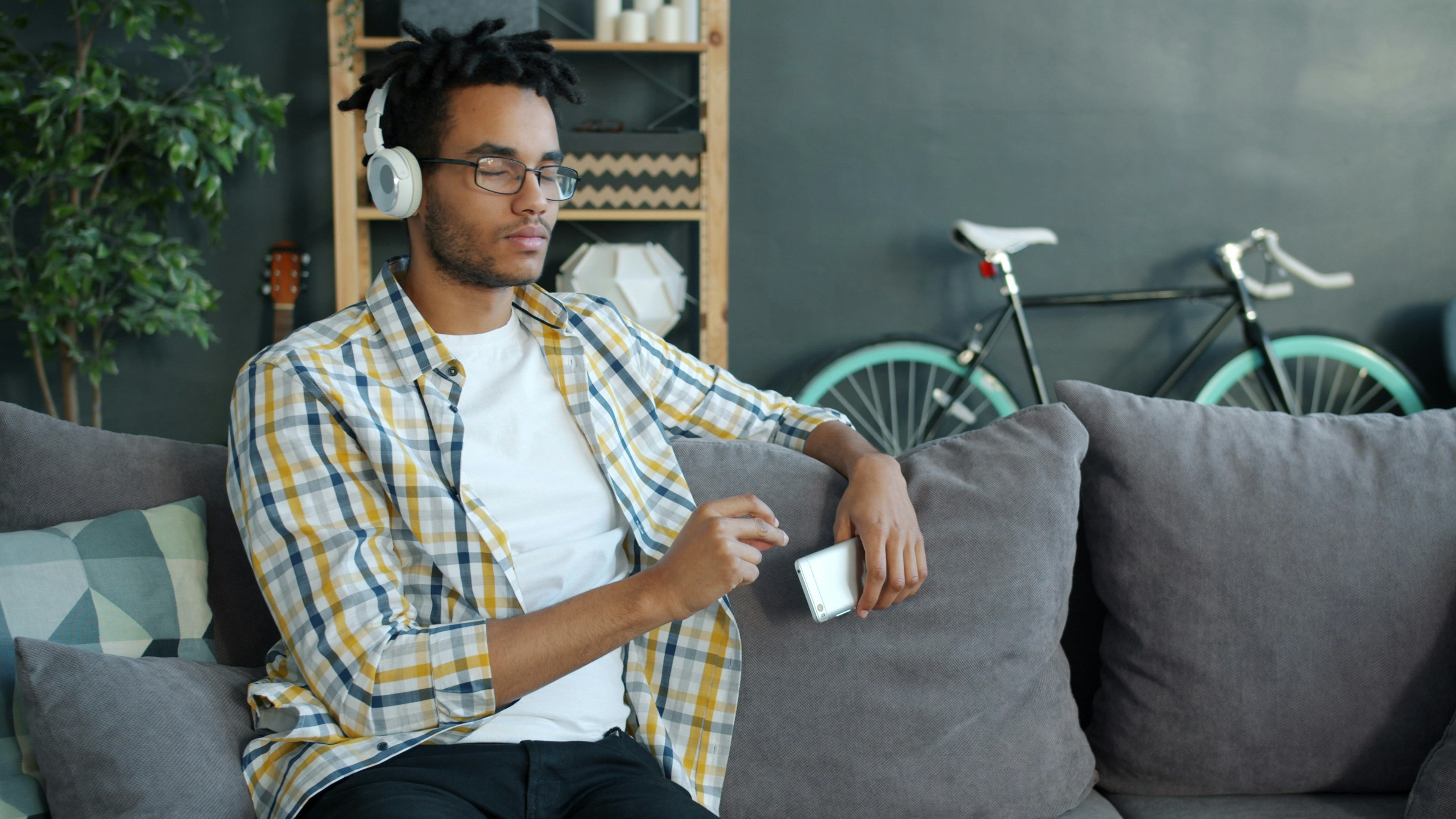 Man wearing headphones listening to music on couch.