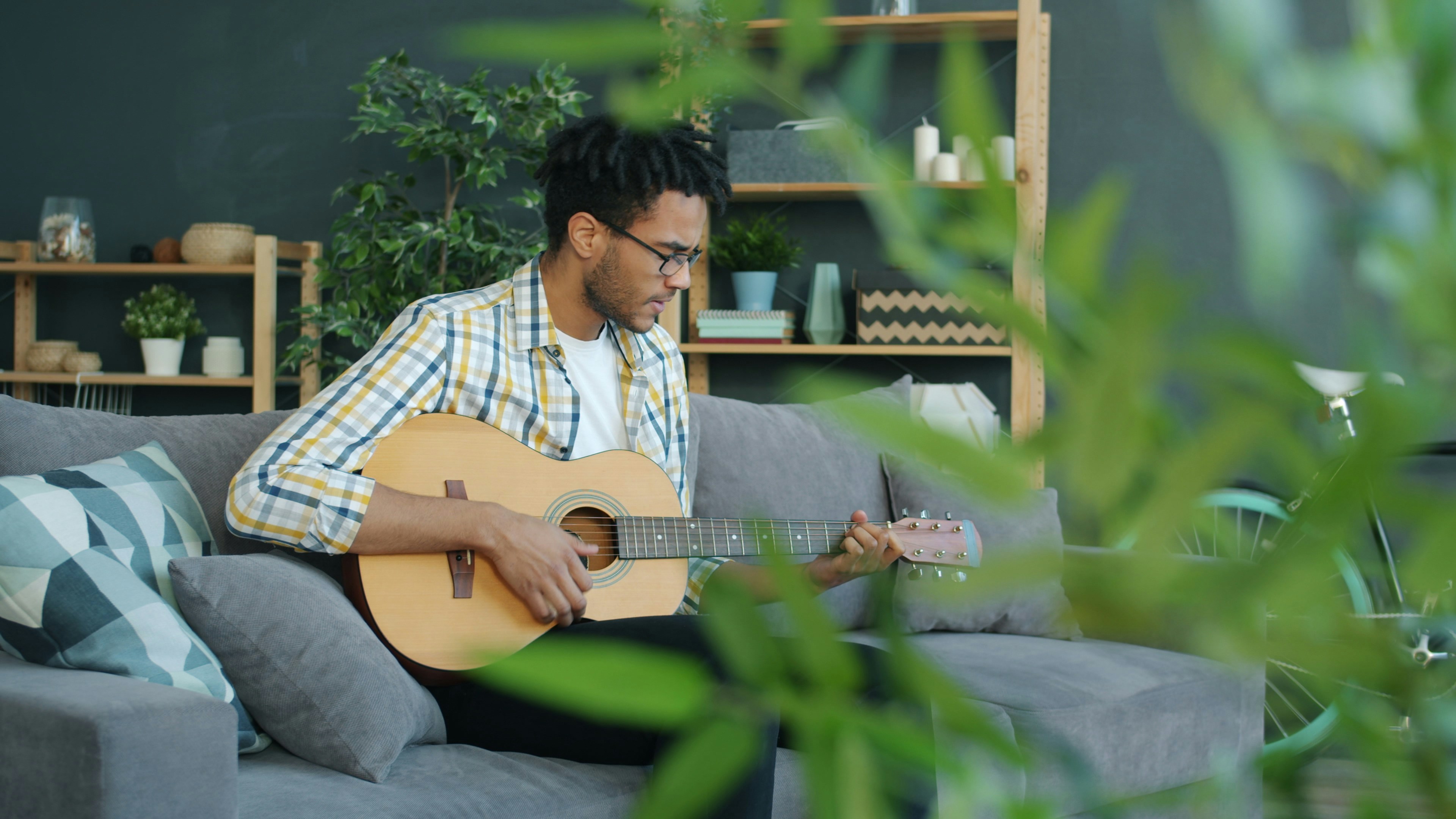 Man playing acoustic guitar on a couch.