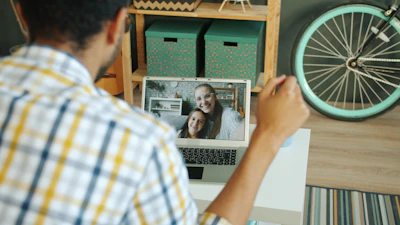 Man video calling two smiling women on laptop.