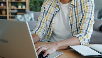 Man typing on laptop with notebook on desk