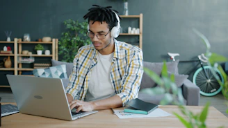 Man with headphones working on laptop at home office.