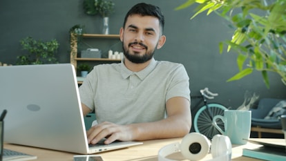 A man smiles while working on a laptop.