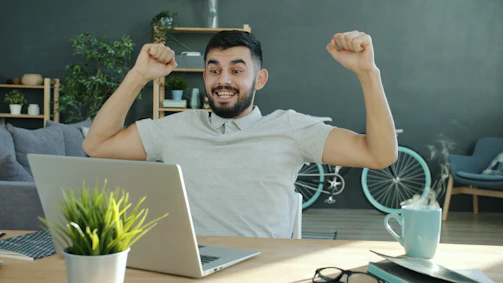 Man celebrating success while working on laptop.