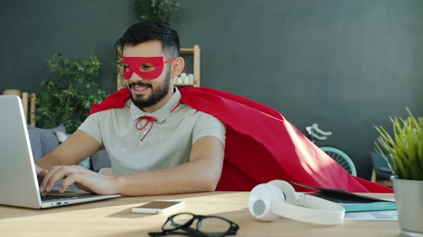 Man in superhero costume working on laptop