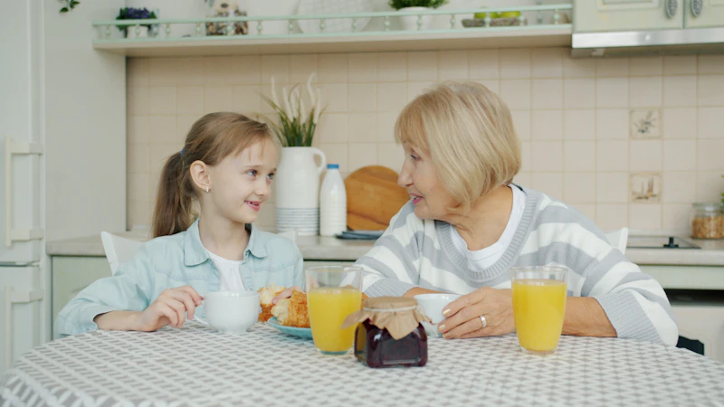 A grandmother and granddaughter laughing over breakfast