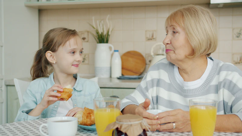 Grandmother and granddaughter enjoying breakfast together at a kitchen table