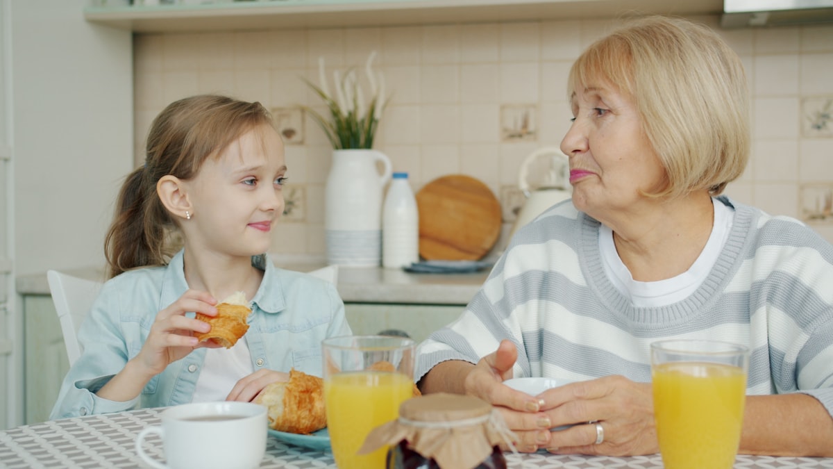 Grandmother and granddaughter sharing breakfast at the table