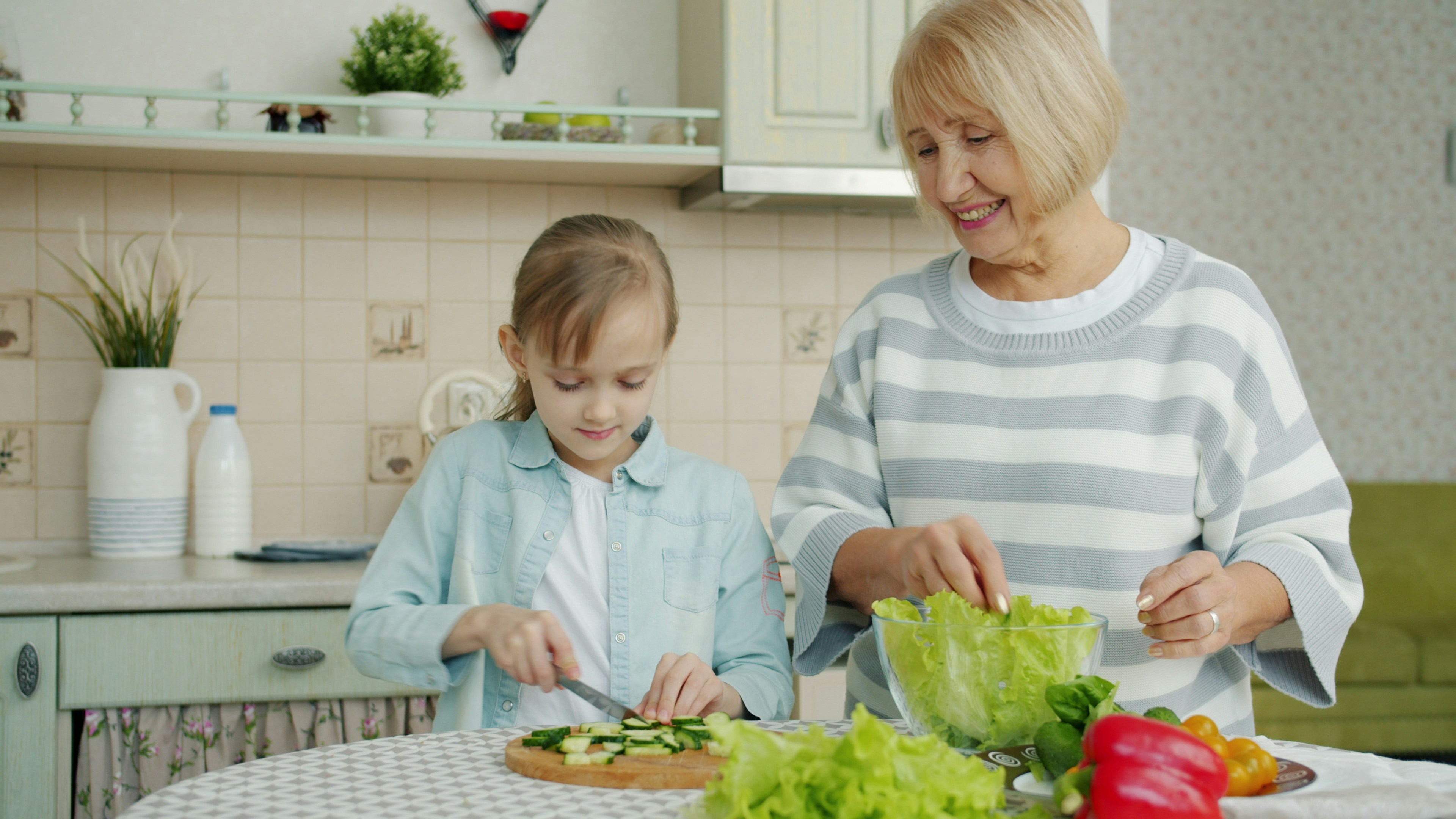 Grandmother and granddaughter preparing food in the kitchen.