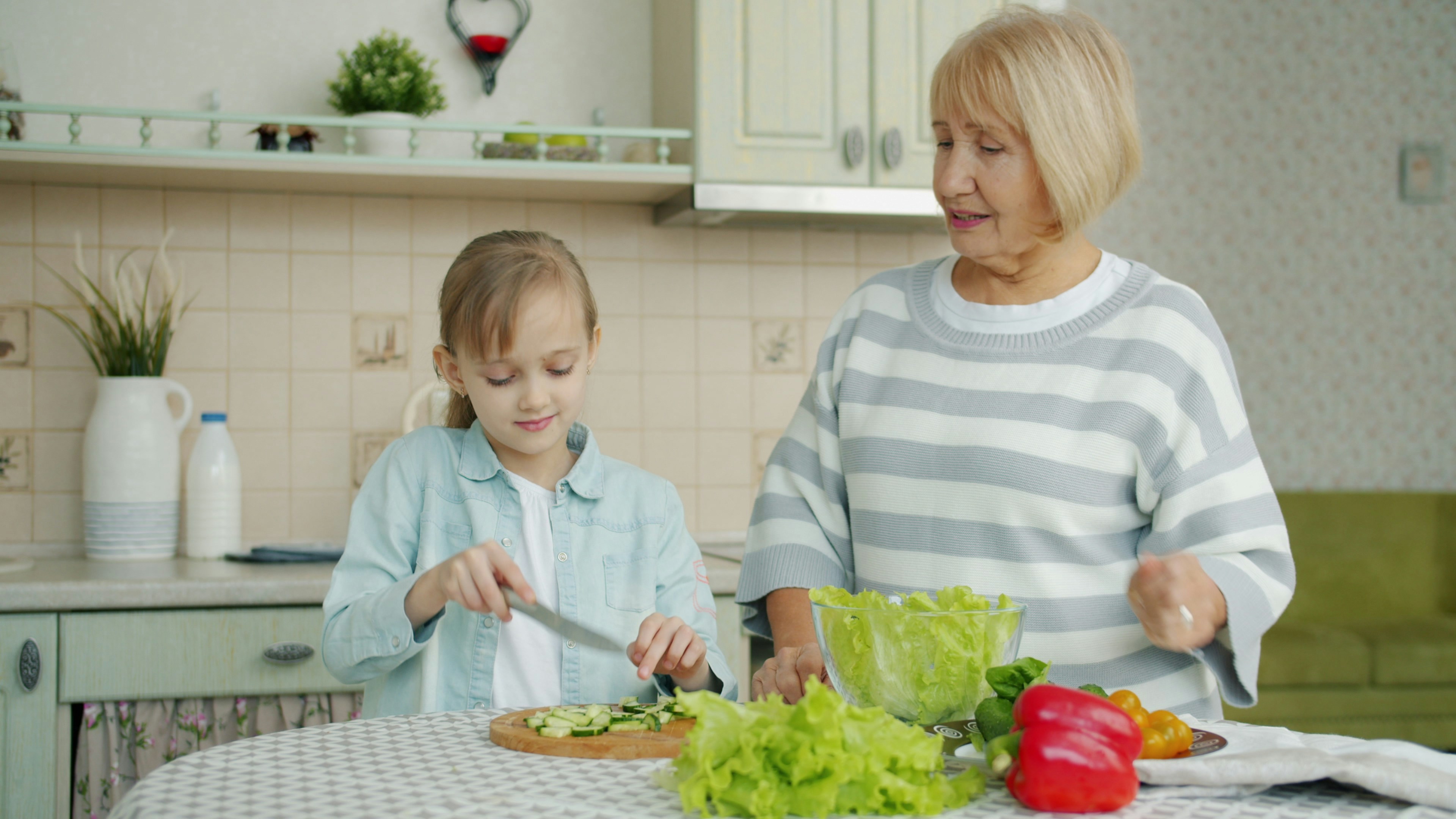 Grandmother and granddaughter preparing salad in kitchen