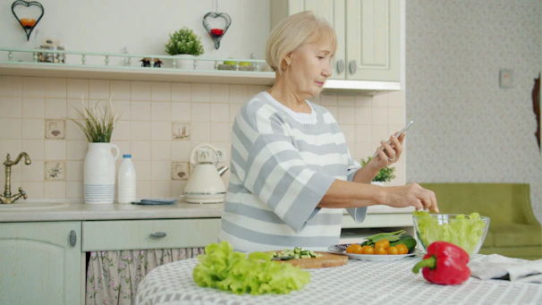 Elderly woman preparing salad in a kitchen