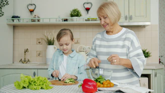 Grandmother and granddaughter preparing salad in kitchen