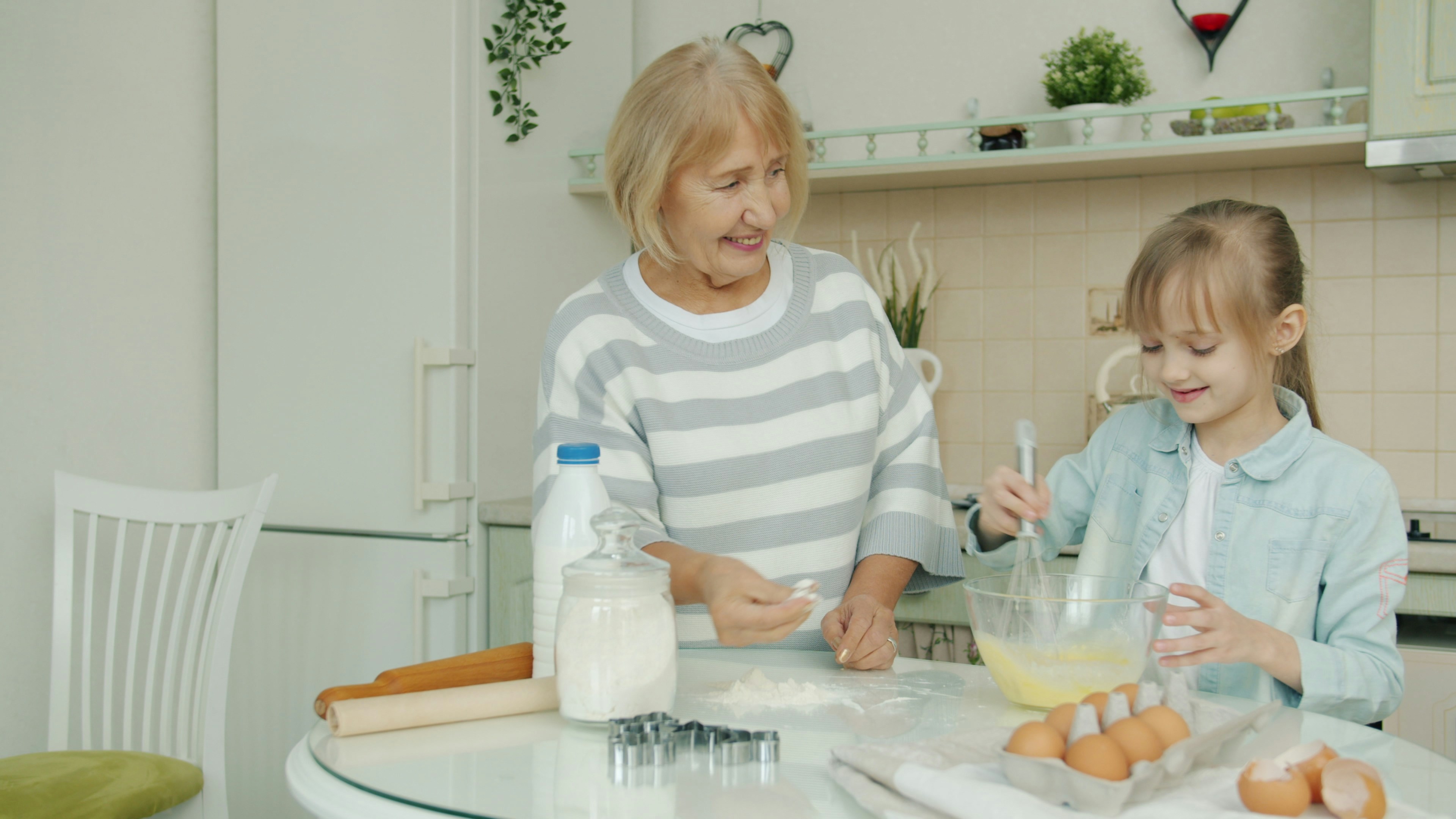 Grandmother and granddaughter baking together in the kitchen.