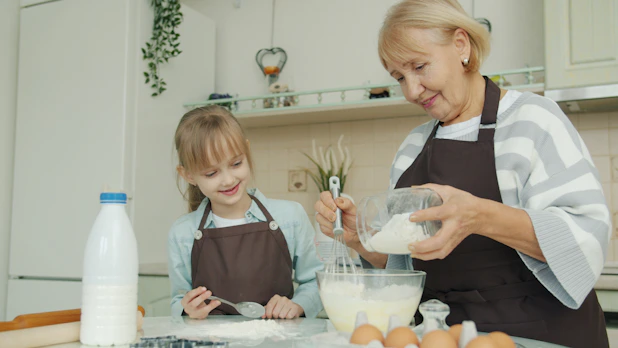 Grandmother and granddaughter baking together in a kitchen.