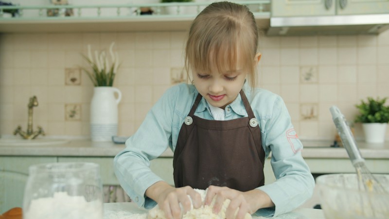Someone in a heavy linen apron working dough on a kitchen counter