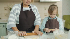 Grandmother and granddaughter baking together in kitchen.