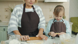 Grandmother and granddaughter baking together in kitchen.