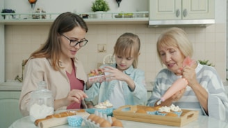 Three women baking and decorating cupcakes in a kitchen.