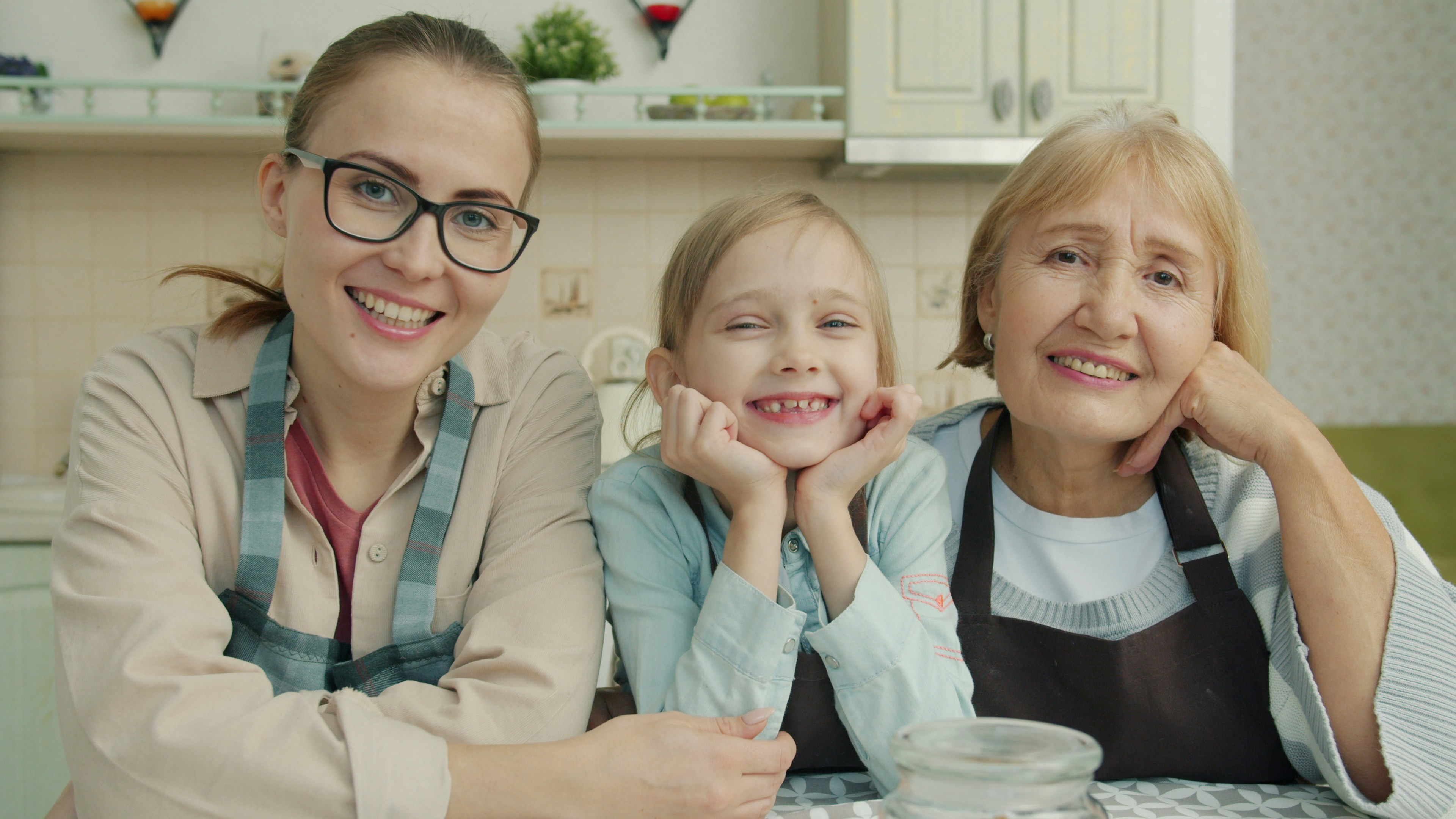 Portrait of joyful family grandmother, mother and daughter smiling in modern kitchen
