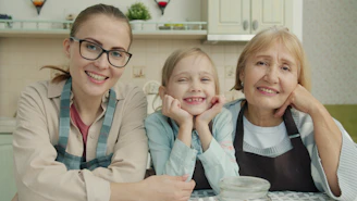Three smiling women of different ages in a kitchen.