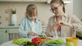 Mother and daughter preparing salad in the kitchen.