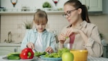 Mother and daughter preparing salad in kitchen.