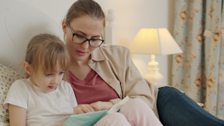 Mother and daughter reading a book together in bed.