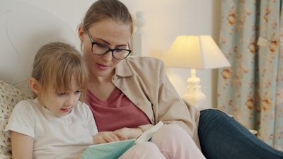 Mother and daughter reading a book together in bed.