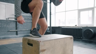 Man performing box jump exercise in gym.