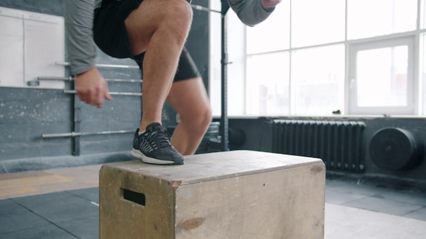 Man performing box jump exercise in gym.