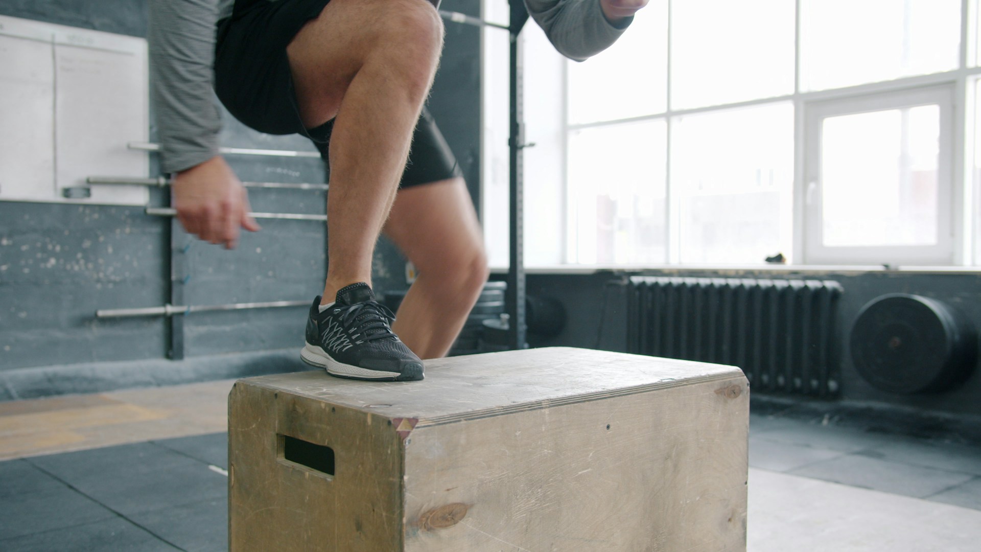 Man performing box jump exercise in gym.