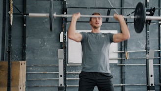 Man lifting heavy barbell overhead in gym