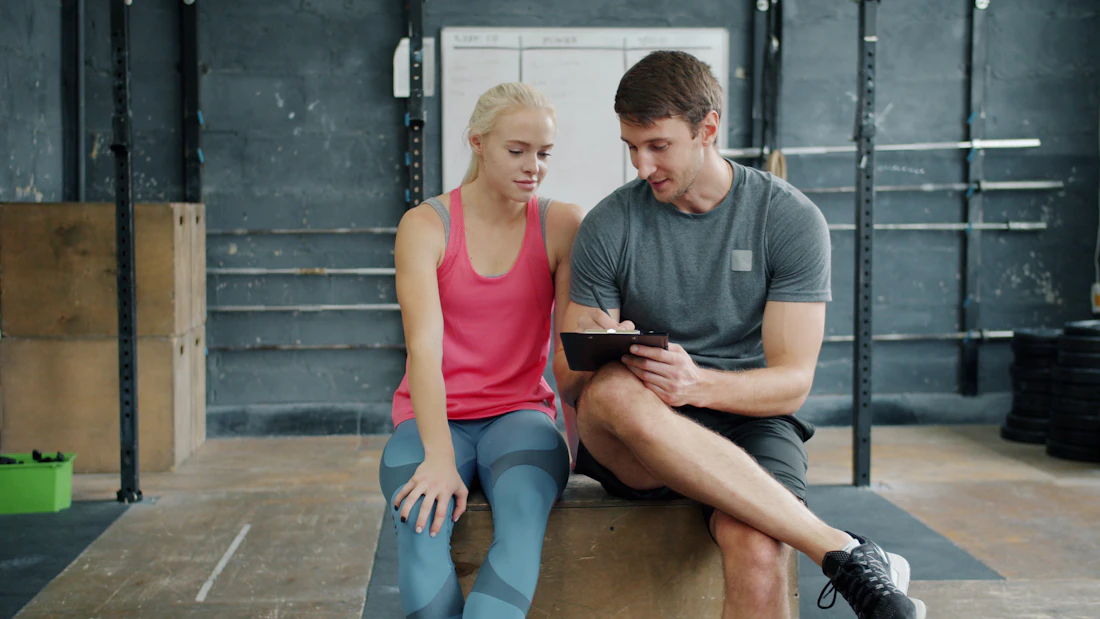 Coach and athlete reviewing training data on a tablet in the gym