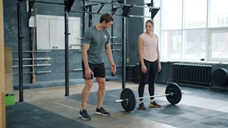 A man and woman with a barbell in a gym.
