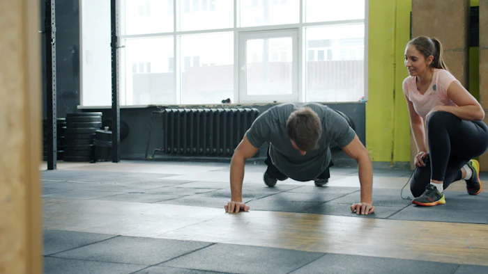A man doing push-ups while a woman spots him