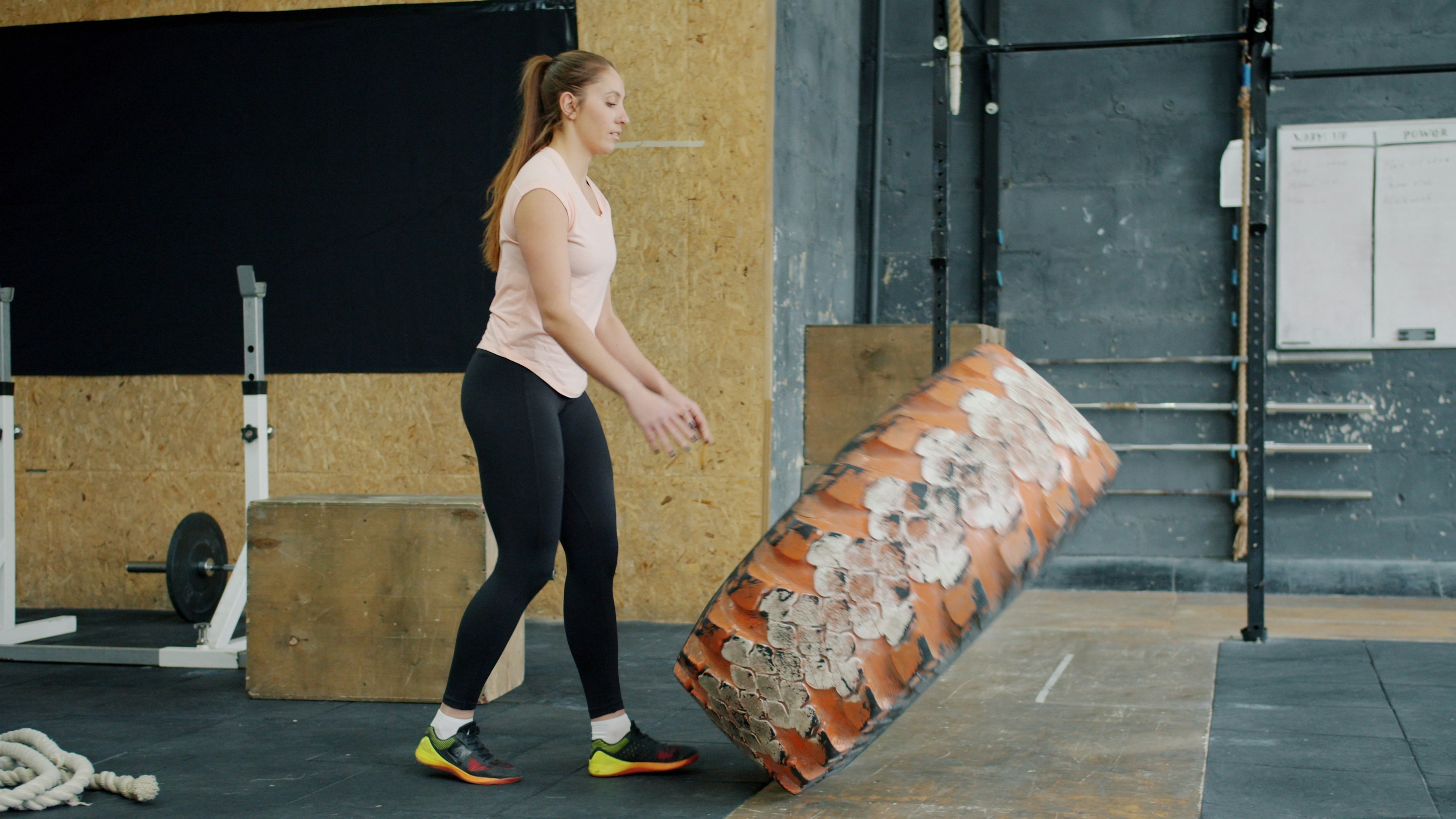 Woman flipping a large tire in a gym.