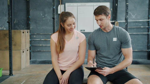 Trainer and client discussing workout plan in gym
