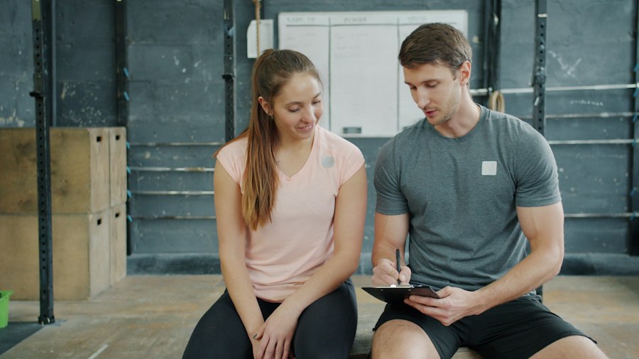 FitForge trainer writing up a new client's intake assessment during an intro session