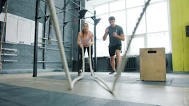 Man and woman exercising with battle ropes.