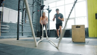 Man and woman exercising with battle ropes.
