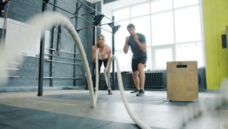 Man and woman exercising with battle ropes.