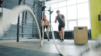 Man and woman exercising with battle ropes.