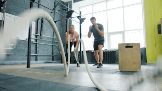 Man and woman exercising with battle ropes.